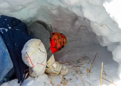 Kid inside a snow cave or quincee during march break camps at the Yukon Wildlife Preserve.